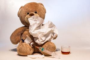 Teddybär mit Taschentuch, Spritze und Hustensaft