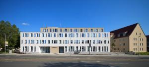 weißes Haus mit vielen Fenstern an Hauptstraße