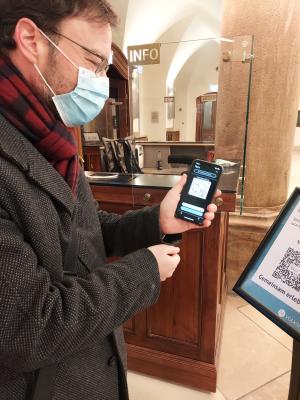 Der Oberbürgermeister präsentiert die luca-App nach dem Check-In. Im Hintergund ist der EIngangsbereich des Volkshauses zu sehen.