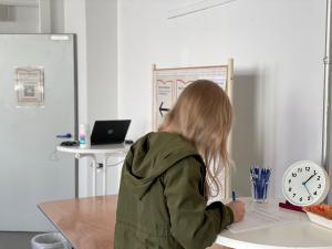 Eine Frau steht in einem Innenraum mit dem Rücken zur Kamera und füllt etwas aus