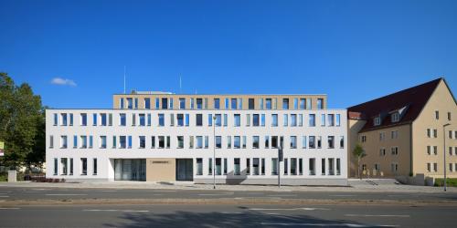 weißes Haus mit vielen Fenstern an Hauptstraße