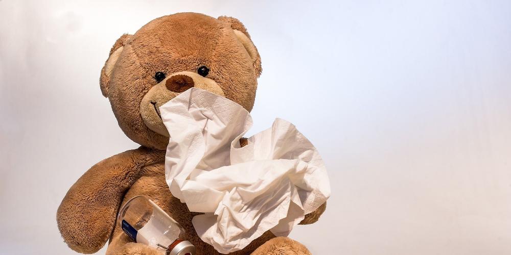 Teddybär mit Taschentuch, Spritze und Hustensaft