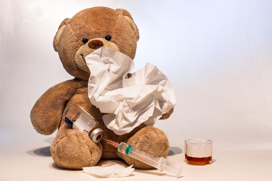 Teddybär mit Taschentuch, Spritze und Hustensaft